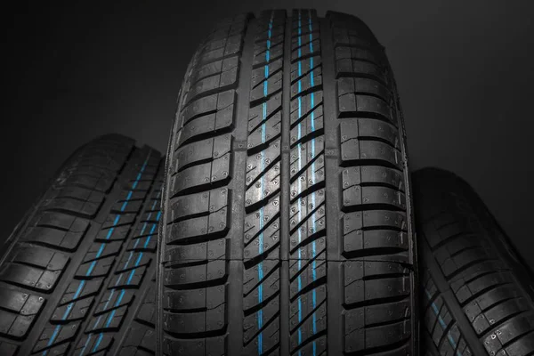 New and unused car tires against dark background — Stock Photo, Image