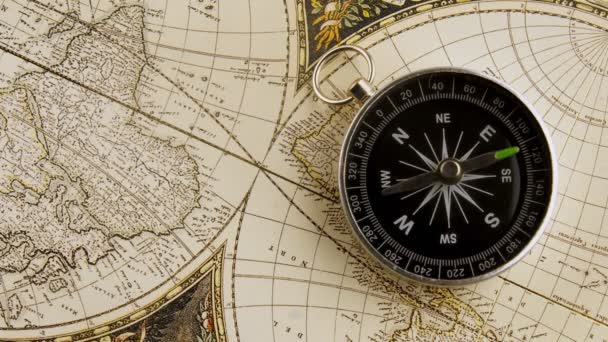 Disorientated spinning compass against map background closeup footage — Stock Video