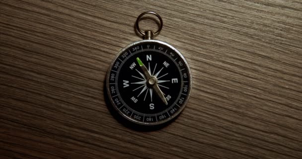 Zdezorientowany kompas spinningowy na tle drewnianego materiału zbliżeniowego — Wideo stockowe