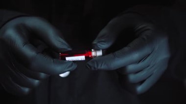 Siyah cerrahi eldivenli mikrobiyolog ya da tıp çalışanının eli hızla yayılan Coronavirus COVID-19