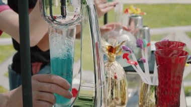 Barmen ve erkek elleri, arka planda hafif bir arka plan üzerine renkli alkollü kokteyl döker.