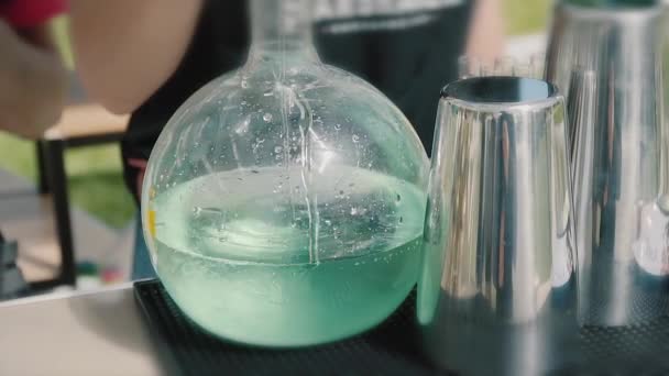 sur un fond clair sur la nature le barman verse un cocktail alcoolique bleu dans une fiole, verre de barman 