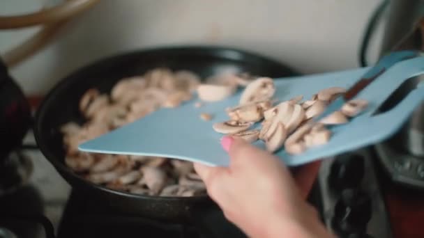 Залить нарезанные грибы в сковороду ножом — стоковое видео