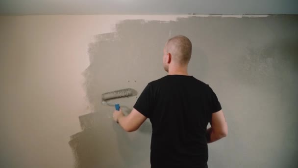 Man schildert een muur thuis achteraanzicht — Stockvideo