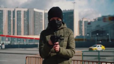 Maskeli kız eldivenlerini karantina sokağına koyar.