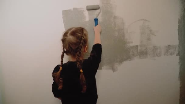 Child paints a wall at home with a roller — Stock Video