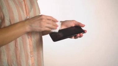 Kadın telefonu antiseptikle yıkıyor.
