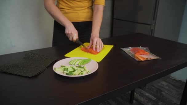 Vrouw snijdt vis op de tafel medium plan — Stockvideo