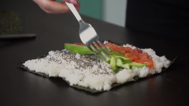 A nő házi sushit készít, uborkát rak rá. — Stock videók