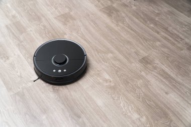 Robot elektrikli süpürge yerdeki siyah temizleme, gri kaplama. Ahşap zemin, akıllı temizlik teknolojisi. Robotik elektrikli süpürge, Akıllı Ev 'i temizliyor..