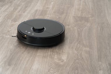 Robot elektrikli süpürge yerdeki siyah temizleme, gri kaplama. Ahşap zemin, akıllı temizlik teknolojisi. Robotik elektrikli süpürge, Akıllı Ev 'i temizliyor..