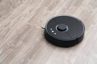 Robot elektrikli süpürge yerdeki siyah temizleme, gri kaplama. Ahşap zemin, akıllı temizlik teknolojisi. Robotik elektrikli süpürge, Akıllı Ev 'i temizliyor..