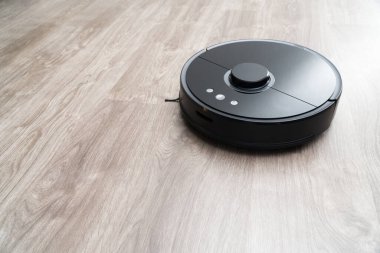 Robot elektrikli süpürge yerdeki siyah temizleme, gri kaplama. Ahşap zemin, akıllı temizlik teknolojisi. Robotik elektrikli süpürge, Akıllı Ev 'i temizliyor..