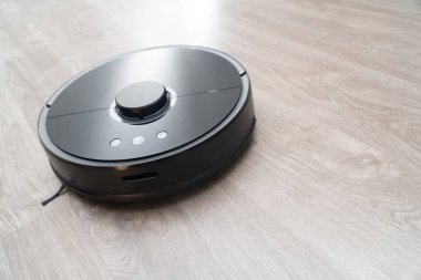 Robot elektrikli süpürge yerdeki siyah temizleme, gri kaplama. Ahşap zemin, akıllı temizlik teknolojisi. Robotik elektrikli süpürge, Akıllı Ev 'i temizliyor..