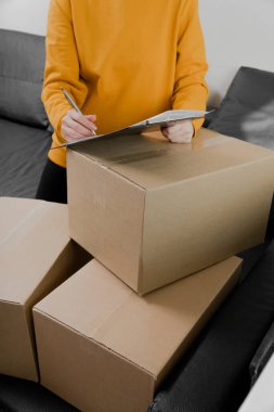 Genç bir kızın yakın çekimi teslimat formuna imza atar. Her şey kartonda paketlenmiş. Müşteri paketini aldı. dikey resim