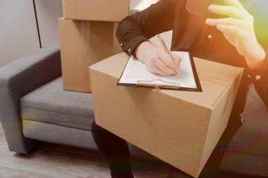 Adam paketi göndermek için bir sipariş formu dolduruyor. Bir karton kutu teslimatla müşteriye gönderilir..