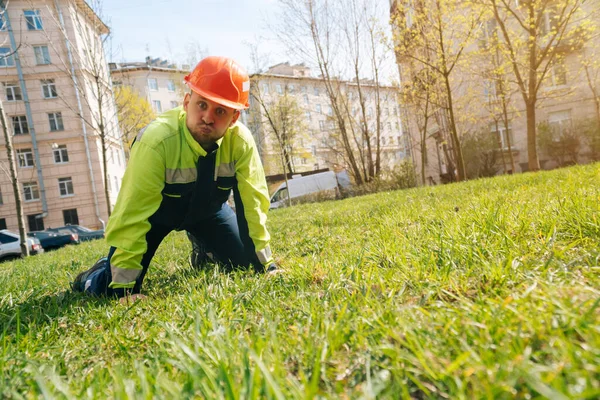 general plan of a male builder European sitting on the grass and indulging. The concept of a cheerful man in workwear after work