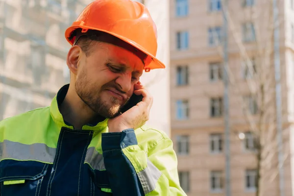 Closeup of a disappointed male construction worker who received an emergency fire call. Fire extinguishing concept on a summer day