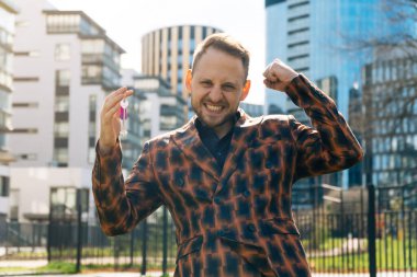 Neşeli genç bir adam dairenin anahtarlarını gösteriyor. Gayrimenkul satın alma kavramı.