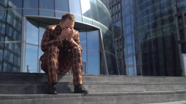 Tıbbi maskeli genç bir adam öksürüyor ve dirseğine hapşırıyor. İnsan hastalığı kavramı.