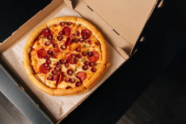 Kurye, karton kutunun üstünde nefis bir pepperoni pizza tutuyor. Fast food teslimatı.