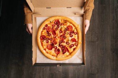 Kadın elleri nefis pepperonili pizza manzarasına sahiptir. Fast food teslimatı.