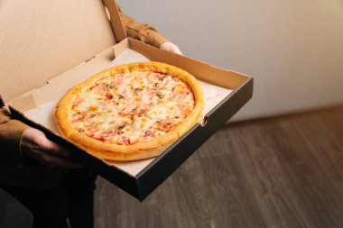 Nefis güzel Prosciutto pizzası ellerinde. Teslimat yeri için fotoğraf ve yazı için boşluk.