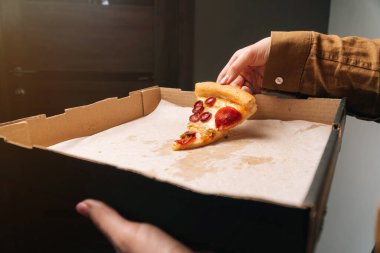 Kız, biberli pizzanın son dilimini yakın plandan alıyor..