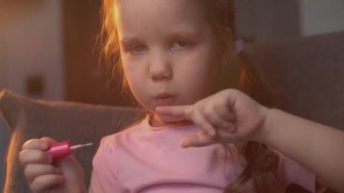 Kafkasyalı bir bebeğin yakın çekimi tırnaklarını pembe cila ile boyuyor. Parmaklar boyandıktan sonra darbe alır..