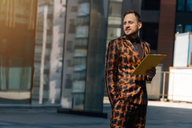 Kafkasyalı bir adam elinde belgelerle tabletle yan tarafa bakıyor. Ofis binasındaki bir iş adamının fotoğrafı..