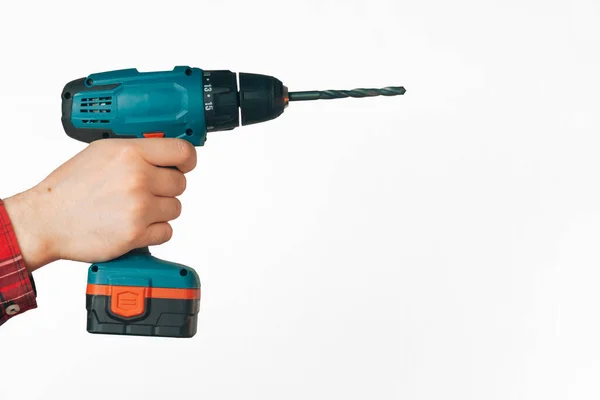male hands hold a drill on a light background. The concept of building tools for furniture assembly. insulation, copy space on white background