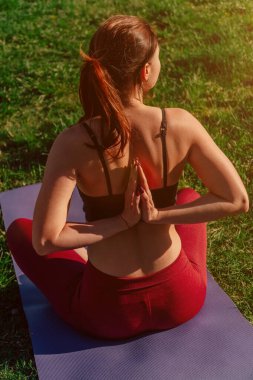 Dikey atış yapan kız sporcu arkadan namaste pozu veriyor. Gün batımında genç kadın kolları açık havada.