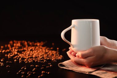 Yakın plan kadın elleri kahve fincanını taze demlenmiş kahveyle tutuyor. Evde sıcaklık ve konfor kavramı, bir içkinin tadını çıkar.