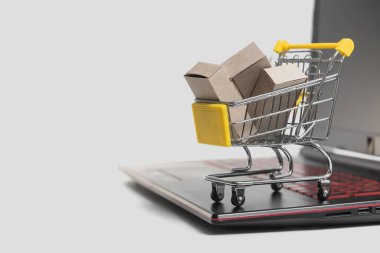 Laptop klavyesinde küçük bir sepetin içinde bir sürü karton kutu. Tüketicilerin internet sitesini kullanarak hem evden hem de ofisten satın alabilecekleri online mağazalar hakkındaki kavramlar