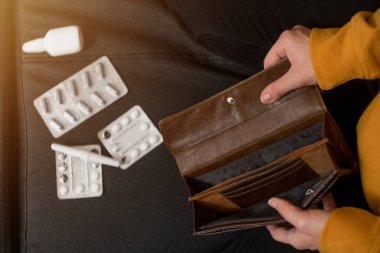 Boş bir cüzdan tutan kadın ellerine yakın çekim. Virüsü, sağlığı ve güvenliği tedavi etmek için uyuşturucuya harcanan para kavramı.
