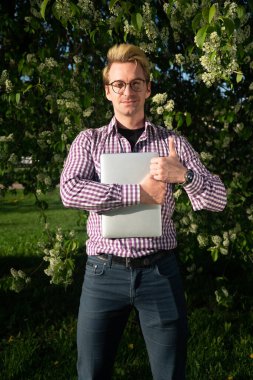 Güneşli bir günde genç sarışın Avrupalı bir adamın dikey portresi. Serbest Çalışan İnternet Konsepti.