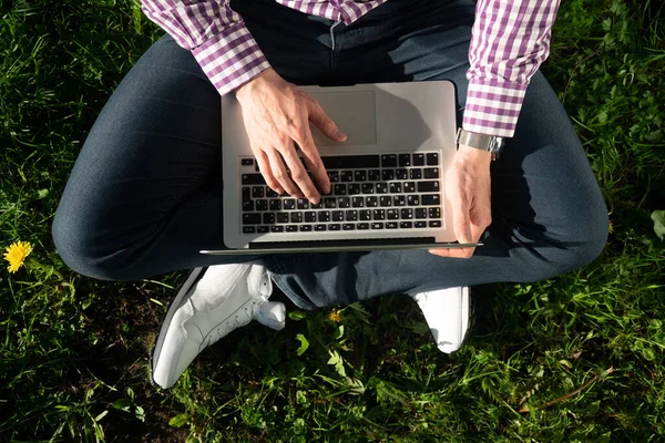 Stock image View from above , young man freelancer is sitting under a tree on a sunny day. working on a laptop. Online concept of online work in the park