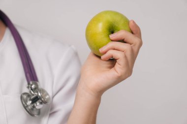 Yakın plan. Diyetisyen genç bir kadın, diyetisyen bir doktor yeşil elma tutuyor. Düzgün beslenme kavramı