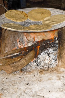 Making tortillas over a wood fire clipart