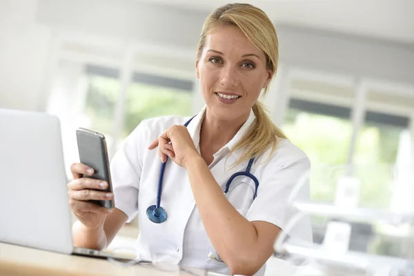 Enfermeira no escritório usando smartphone Imagens Royalty-Free
