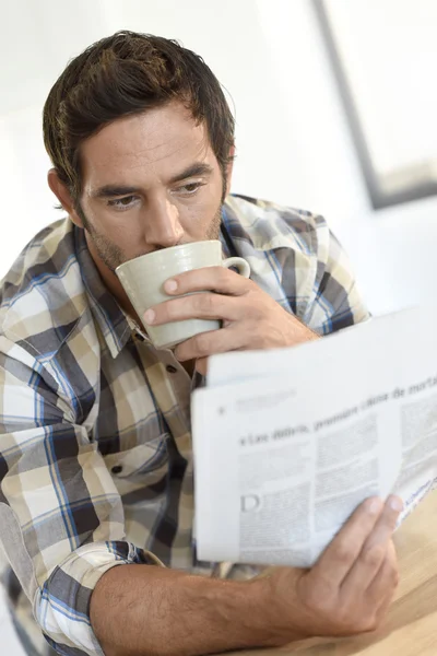 Человек дома читает газету — стоковое фото