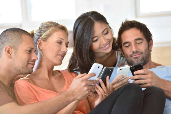 Amigos en casa jugando con teléfonos inteligentes — Foto de Stock
