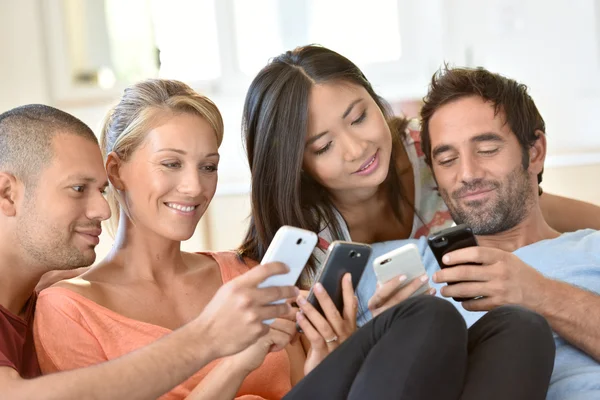 Vrienden thuis spelen met smartphones — Stockfoto