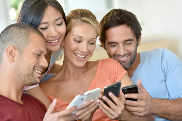 Amigos en casa jugando con teléfonos inteligentes —  Fotos de Stock