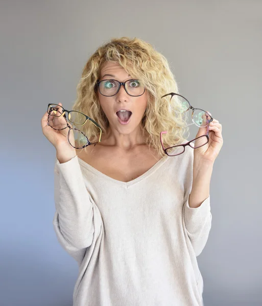 Frau wählt zwischen verschiedenen Brillen — Stockfoto