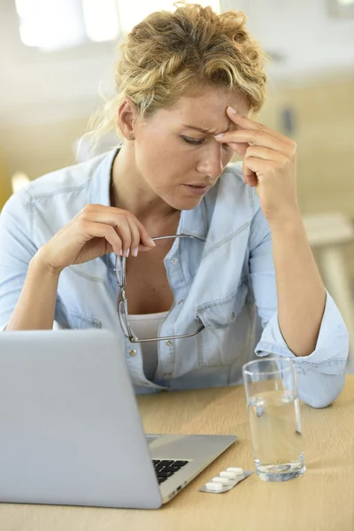 Woman at work taking pill — Stockfoto