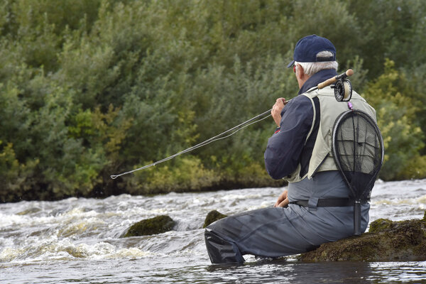 Fly-fisherman waiting with fishing pole