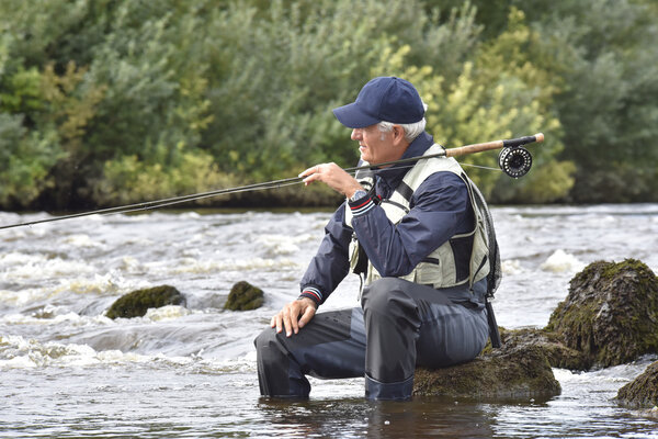 Fly-fisherman waiting with fishing pole
