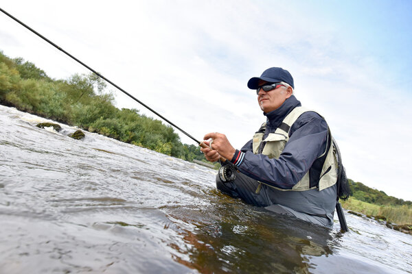 Fly fisherman fishing in river
