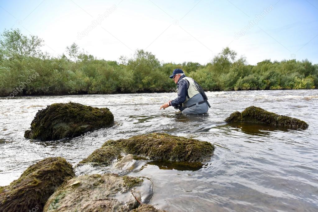 Fly fisherman fishing in river